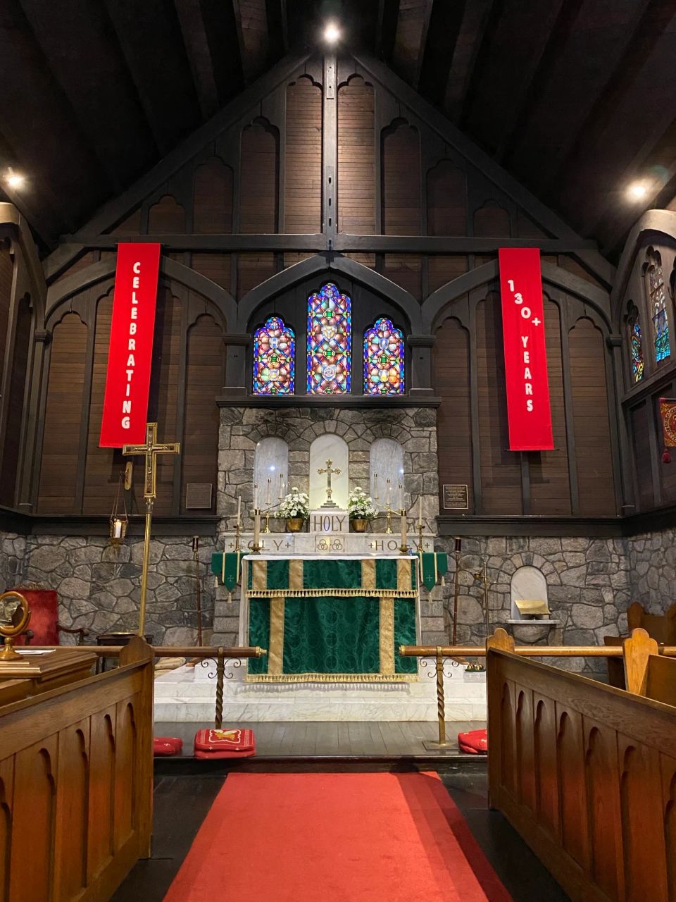 Inside the church with stained glass windows and two red banners celebrating 130+ years of the parish.